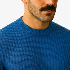 Homem elegante usando suéter de lã azul com textura canelada, gola careca e calça chino bege. Visual sofisticado para o inverno