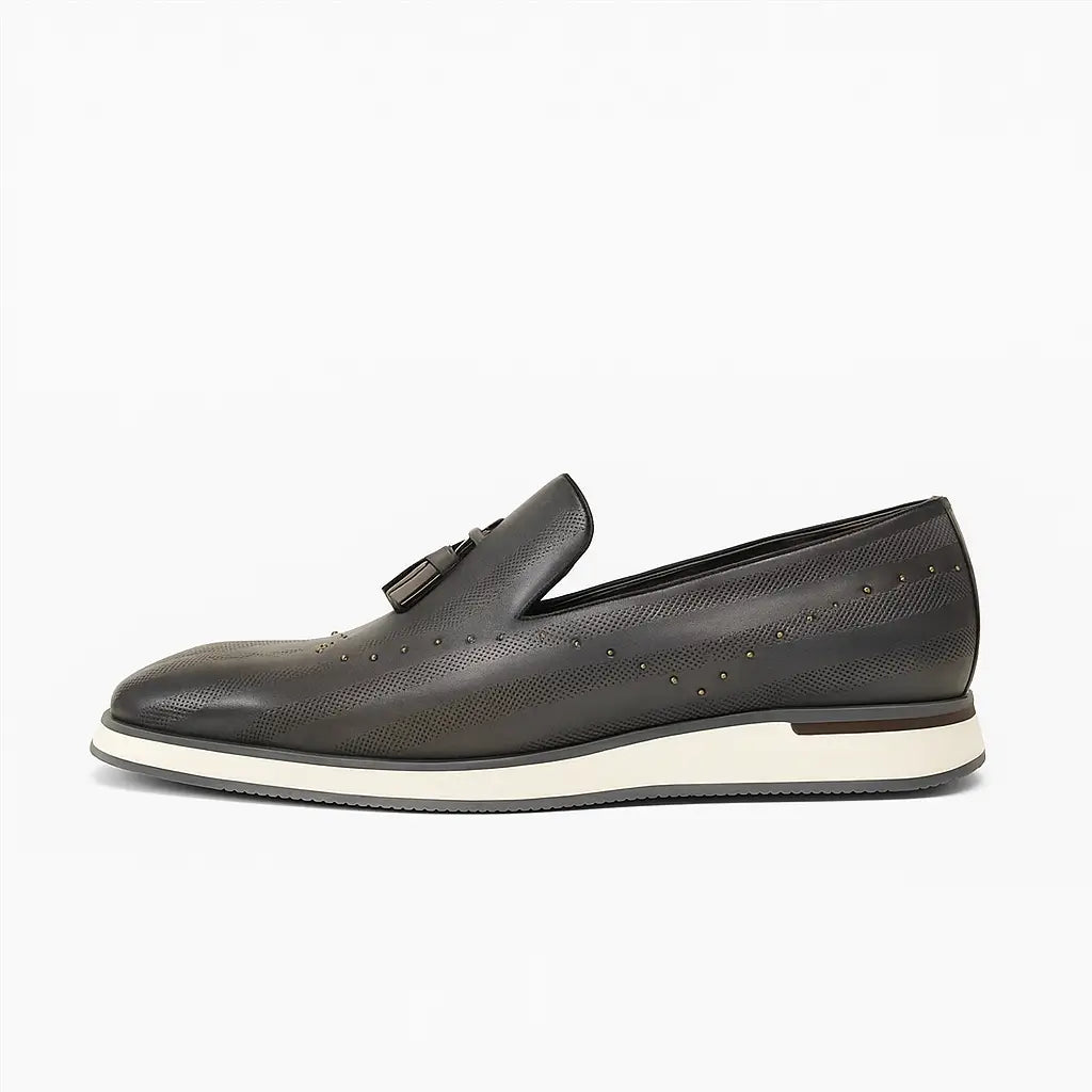 Loafer masculino com tassel e tachas metálicas, couro legítimo texturizado, solado branco e design sofisticado e moderno.