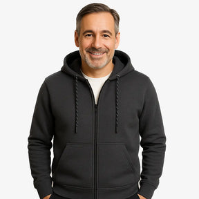 Homem vestindo blusa moletom masculina cinza com capuz e zíper, estilo casual urbano para dias frios, com mãos nos bolsos e camiseta branca por baixo.