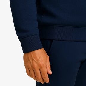 Homem vestindo blusa moletom masculina azul marinho com capuz e zíper, estilo casual urbano para dias frios, com mãos nos bolsos e camiseta branca por baixo.