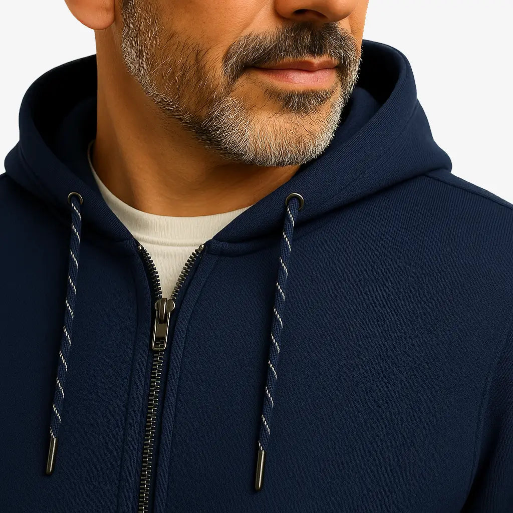 Homem vestindo blusa moletom masculina azul marinho com capuz e zíper, estilo casual urbano para dias frios, com mãos nos bolsos e camiseta branca por baixo.