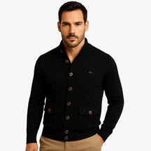 Modelo masculino usando cardigan preto de botão com bolsos frontais, estilo social casual, calça chino bege. Ideal para outono/inverno