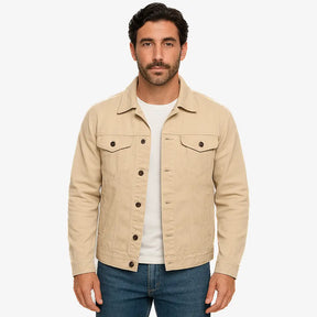 Homem vestindo jaqueta jeans masculina bege com botões, bolsos frontais e gola tradicional, combinada com camiseta branca e calça jeans azul.