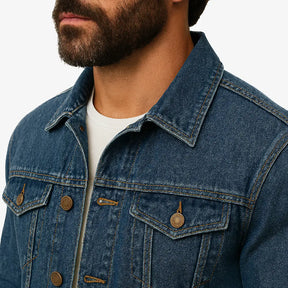 Homem vestindo jaqueta jeans masculina azul jeans com botões, bolsos frontais e gola tradicional, combinada com camiseta branca e calça jeans azul.