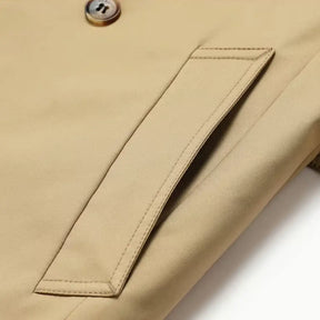 Trench coat masculino com cinto, abotoamento duplo, gola clássica e estilo britânico elegante.