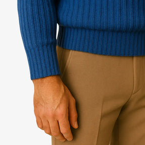 Homem elegante usando suéter de lã azul com textura canelada, gola careca e calça chino bege. Visual sofisticado para o inverno